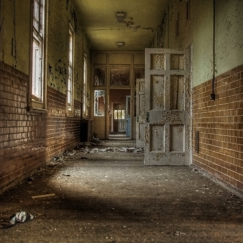 Haunting image of a derelict Victorian corridor with broken walls and faint light at the far end