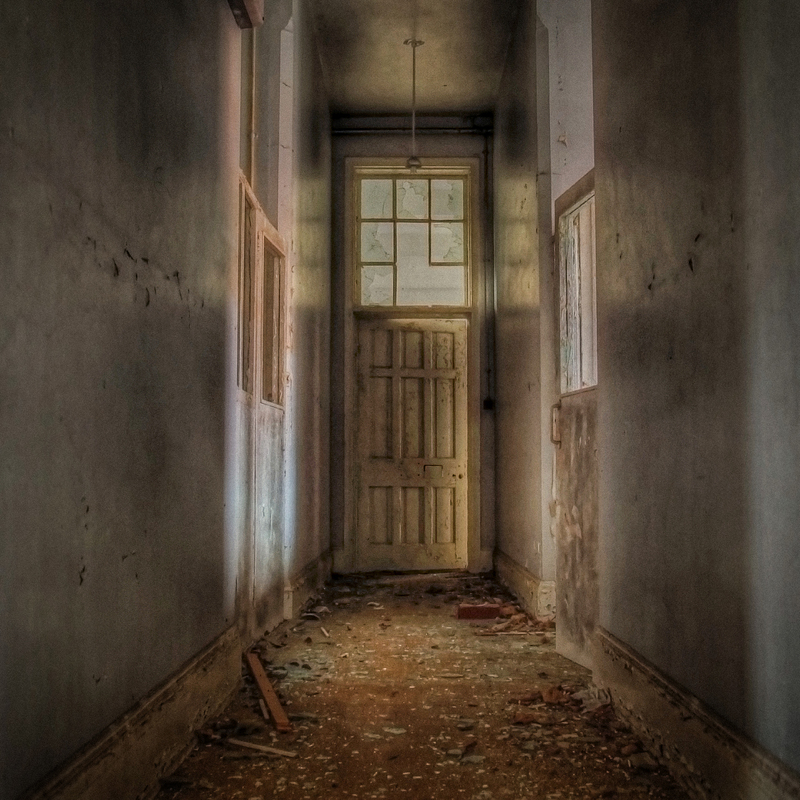 Abandoned Victorian institution corridor, stripped bare and filled with a haunting sense of emptiness